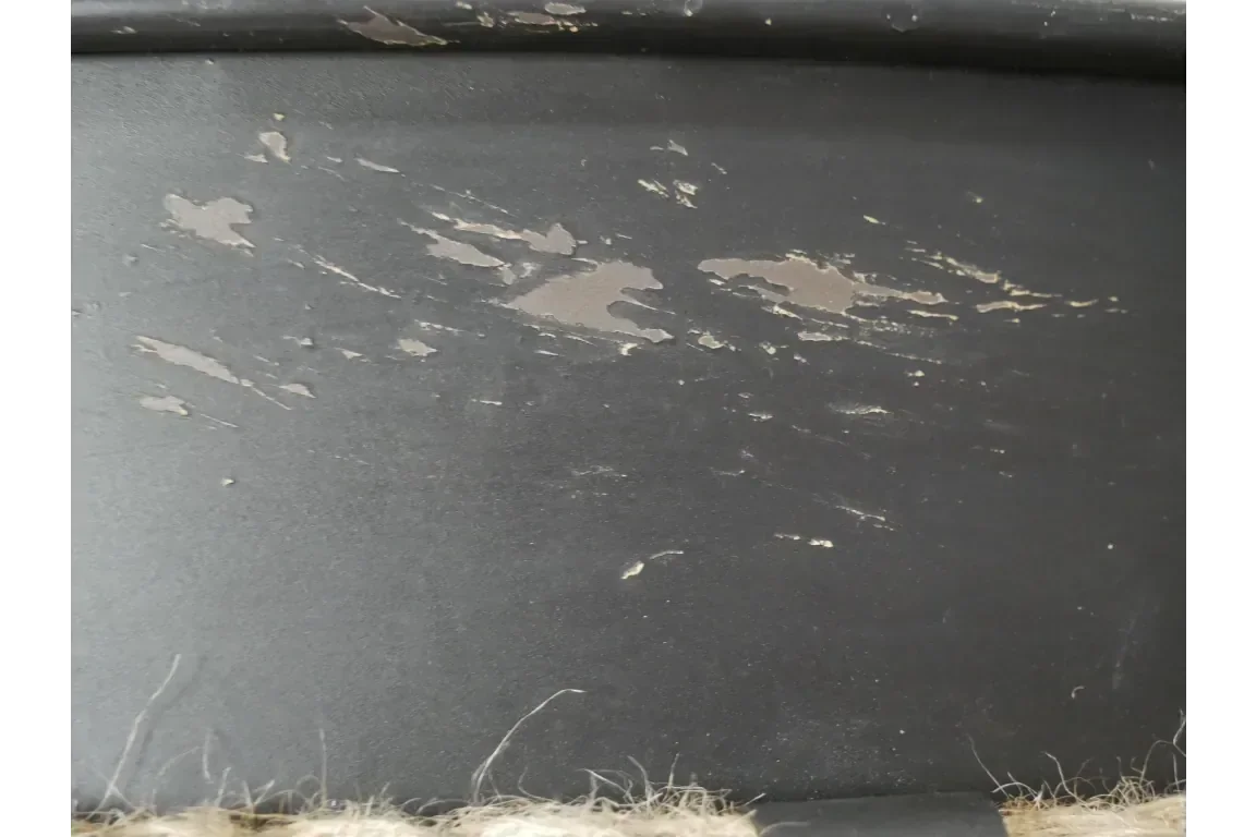 Close-up of worn black painted wood with visible scratches and chipped surface