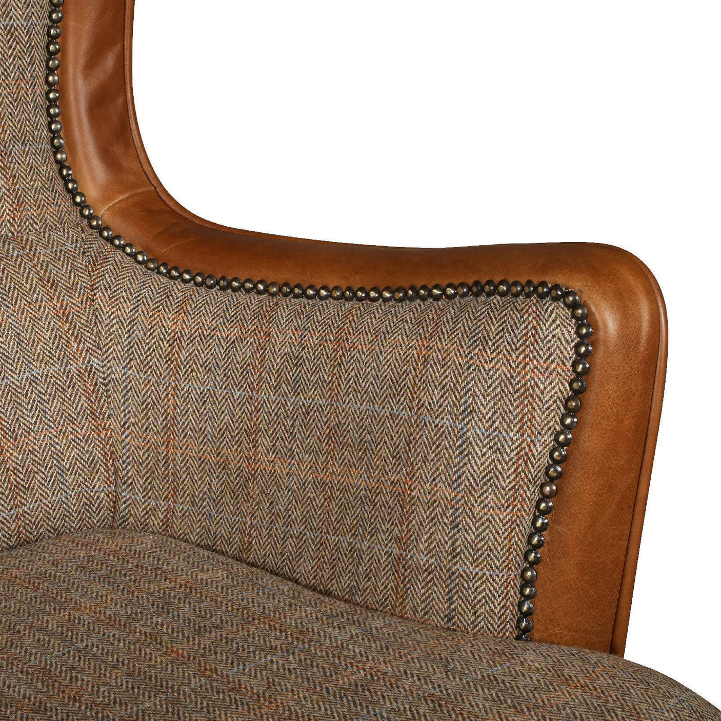 Close-up of tweed and brown leather armchair with brass stud detailing