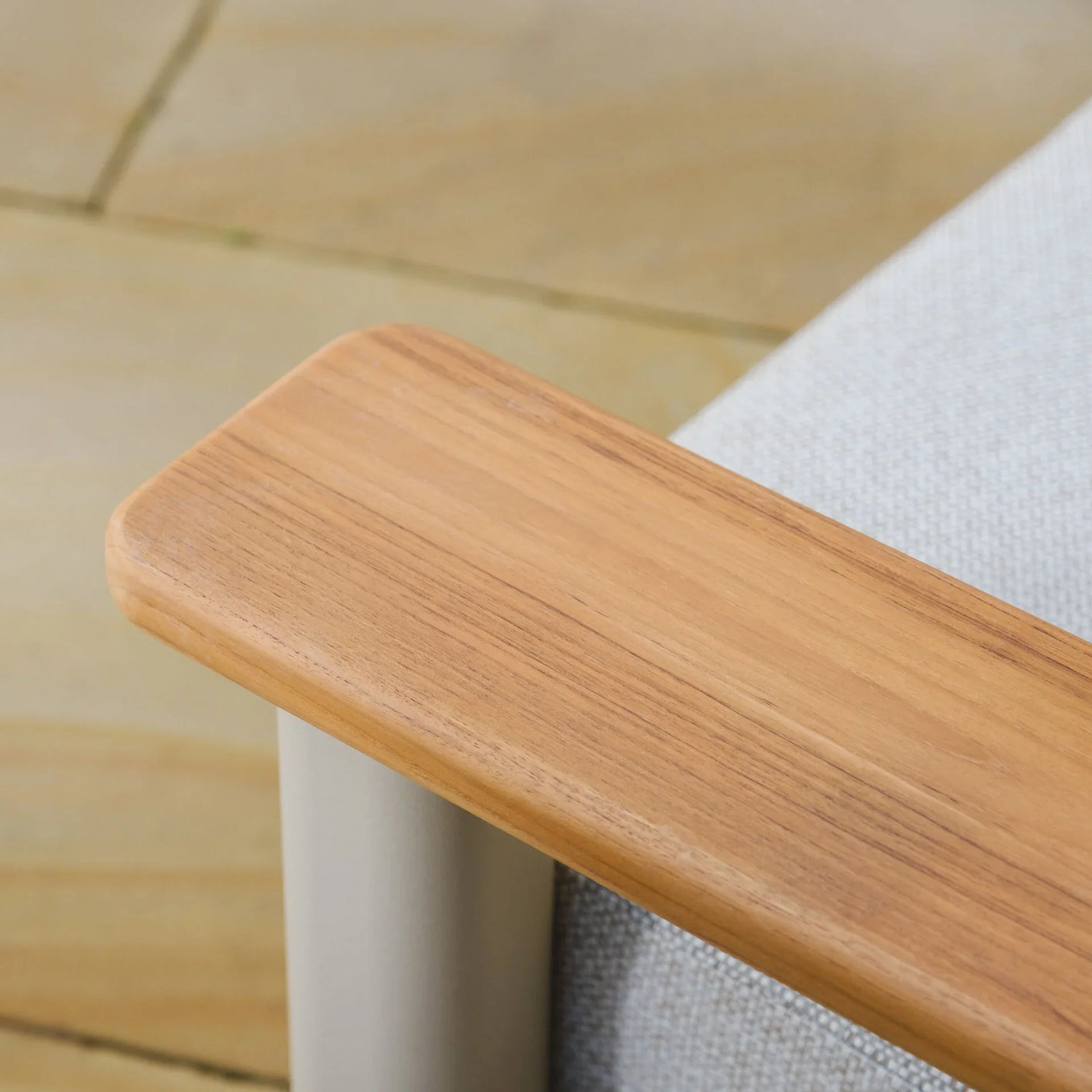 Close detail of wooden armrest on outdoor sofa with light grey fabric cushion