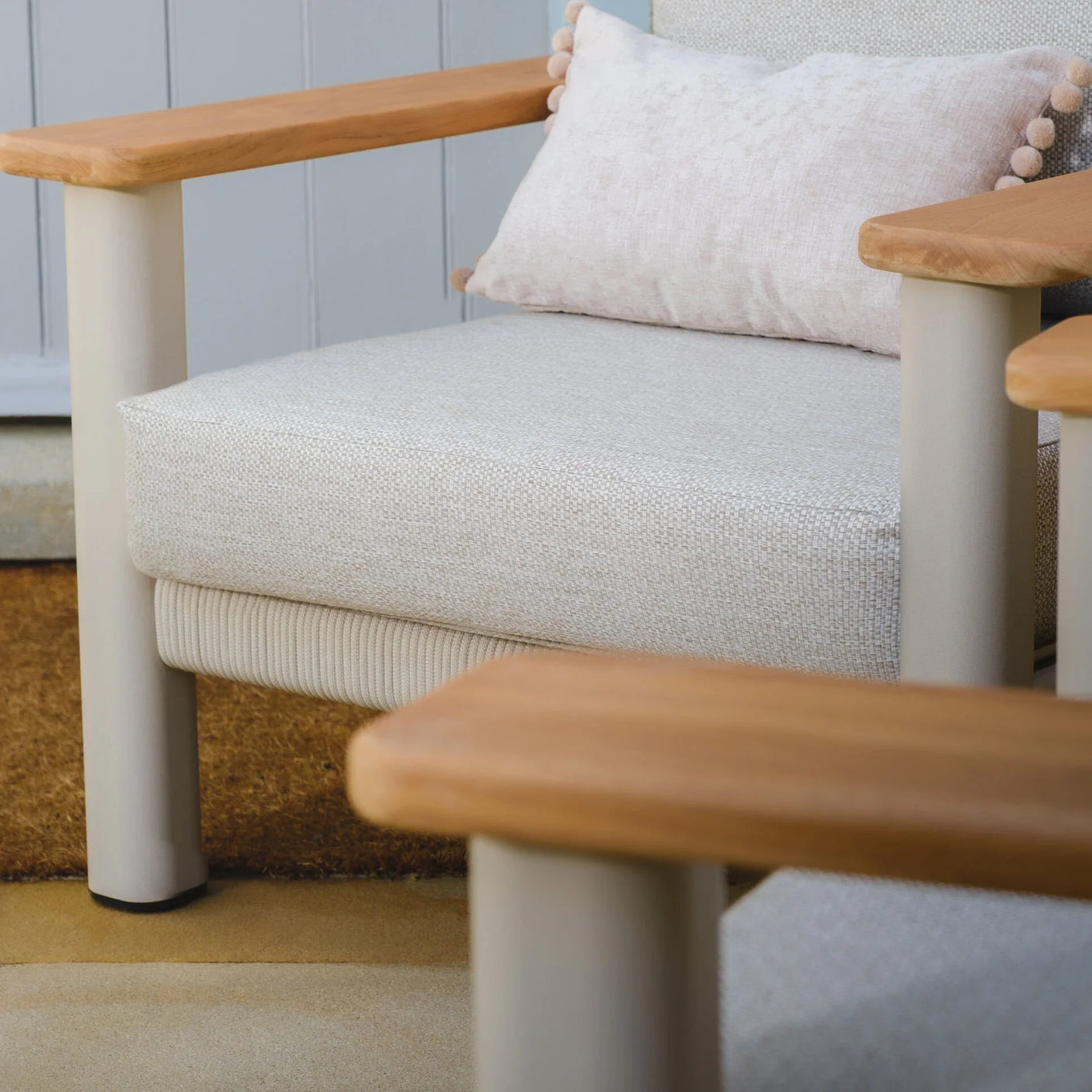 Beige outdoor armchair with wooden armrests and textured cushion, close view
