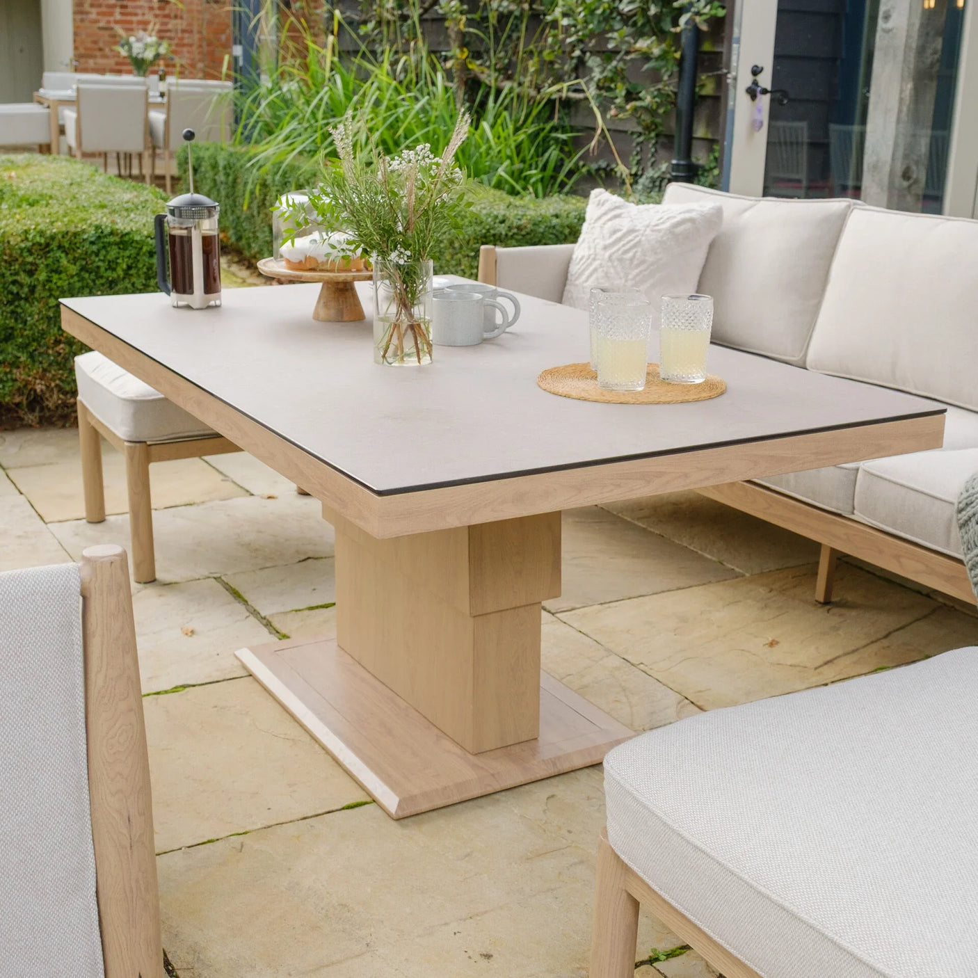 Rectangular wooden outdoor dining table with cream cushioned garden sofa and chairs