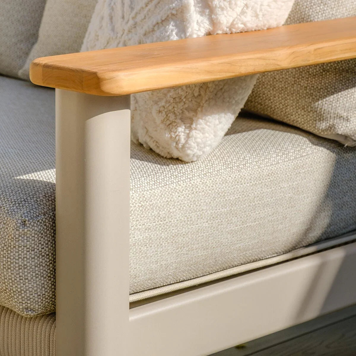 Cream fabric sofa with light wooden armrest and textured cushion detail, corner closeup
