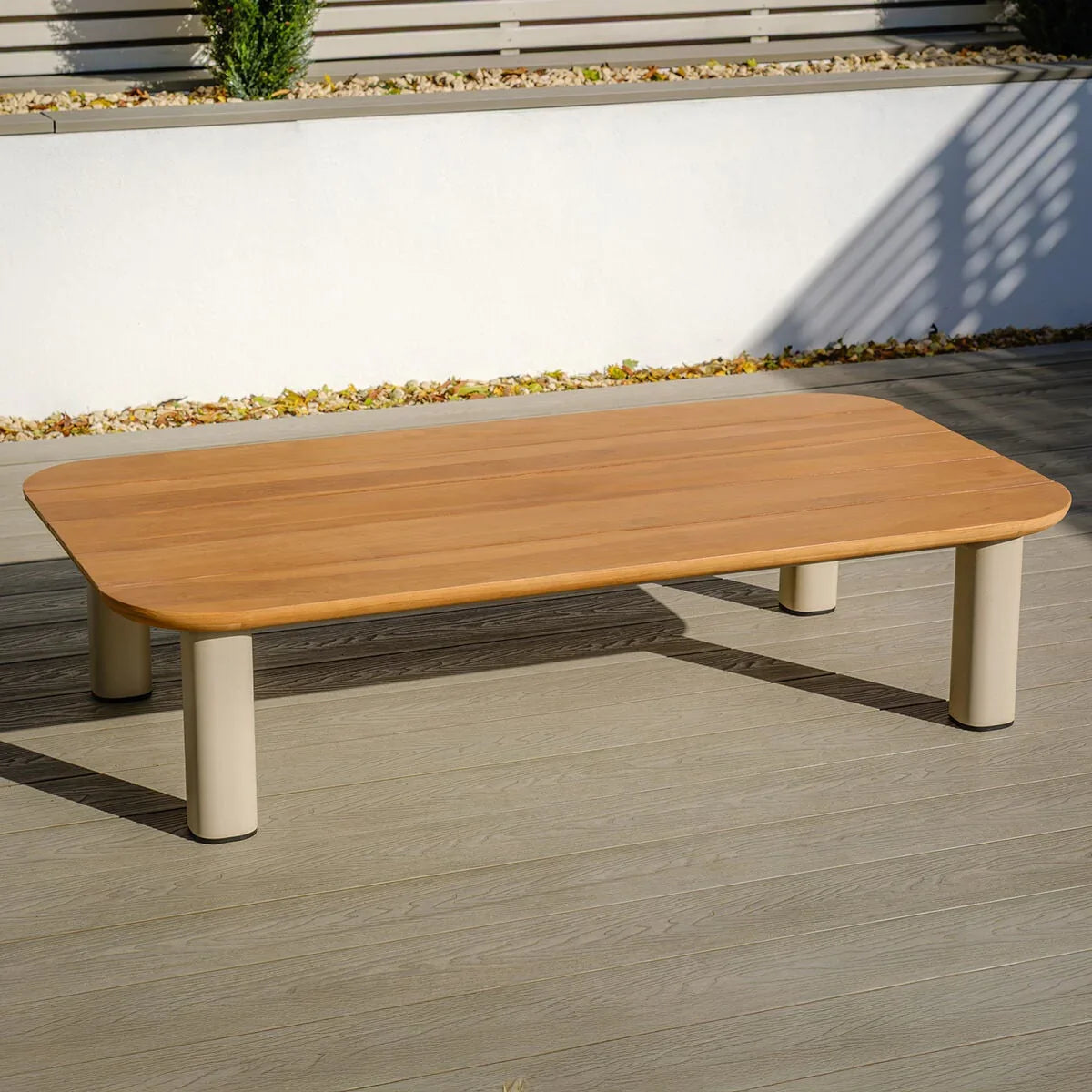 Rectangular outdoor coffee table with wood-effect top and beige legs on patio decking