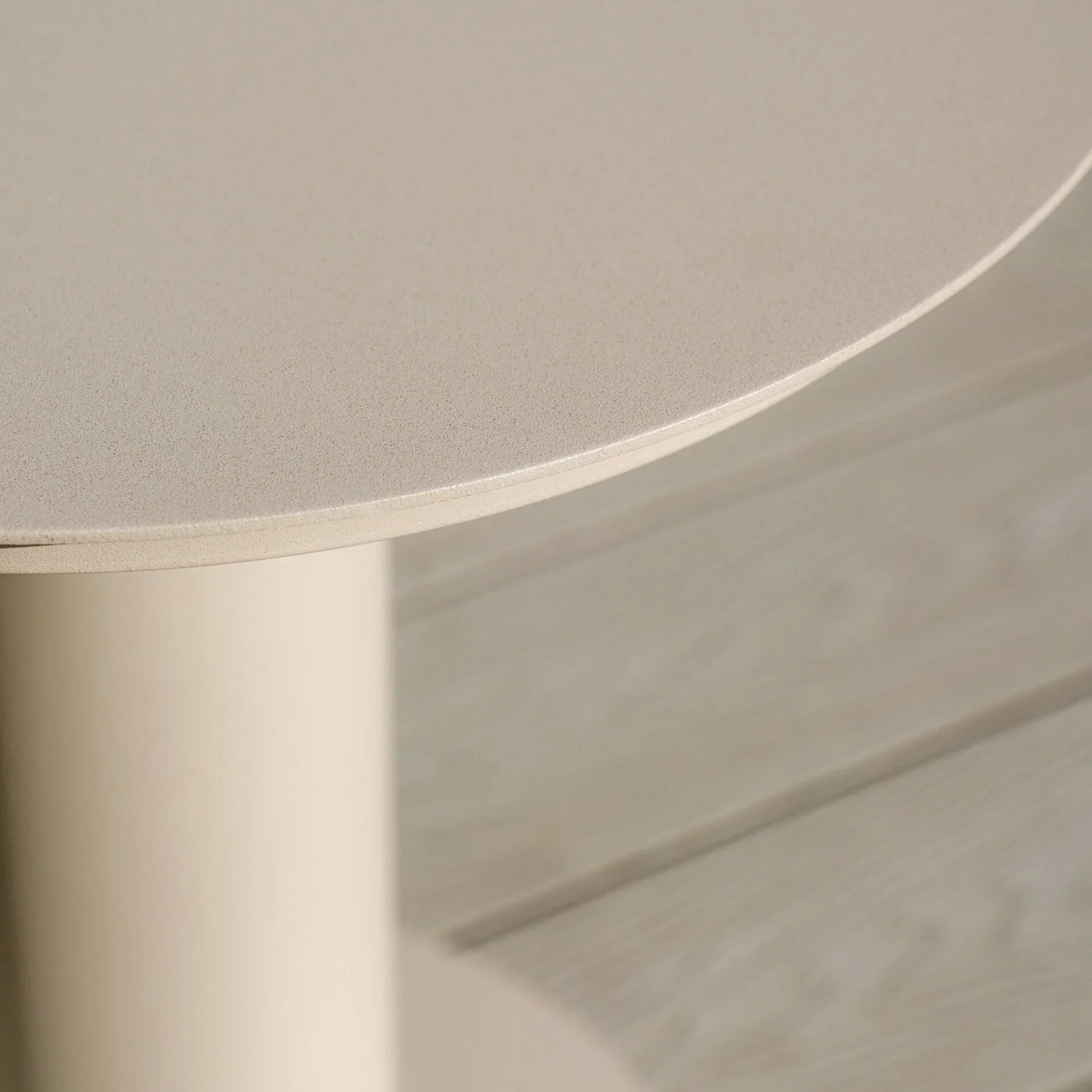 Beige round side table with smooth finish, close-up of tabletop and cylindrical base