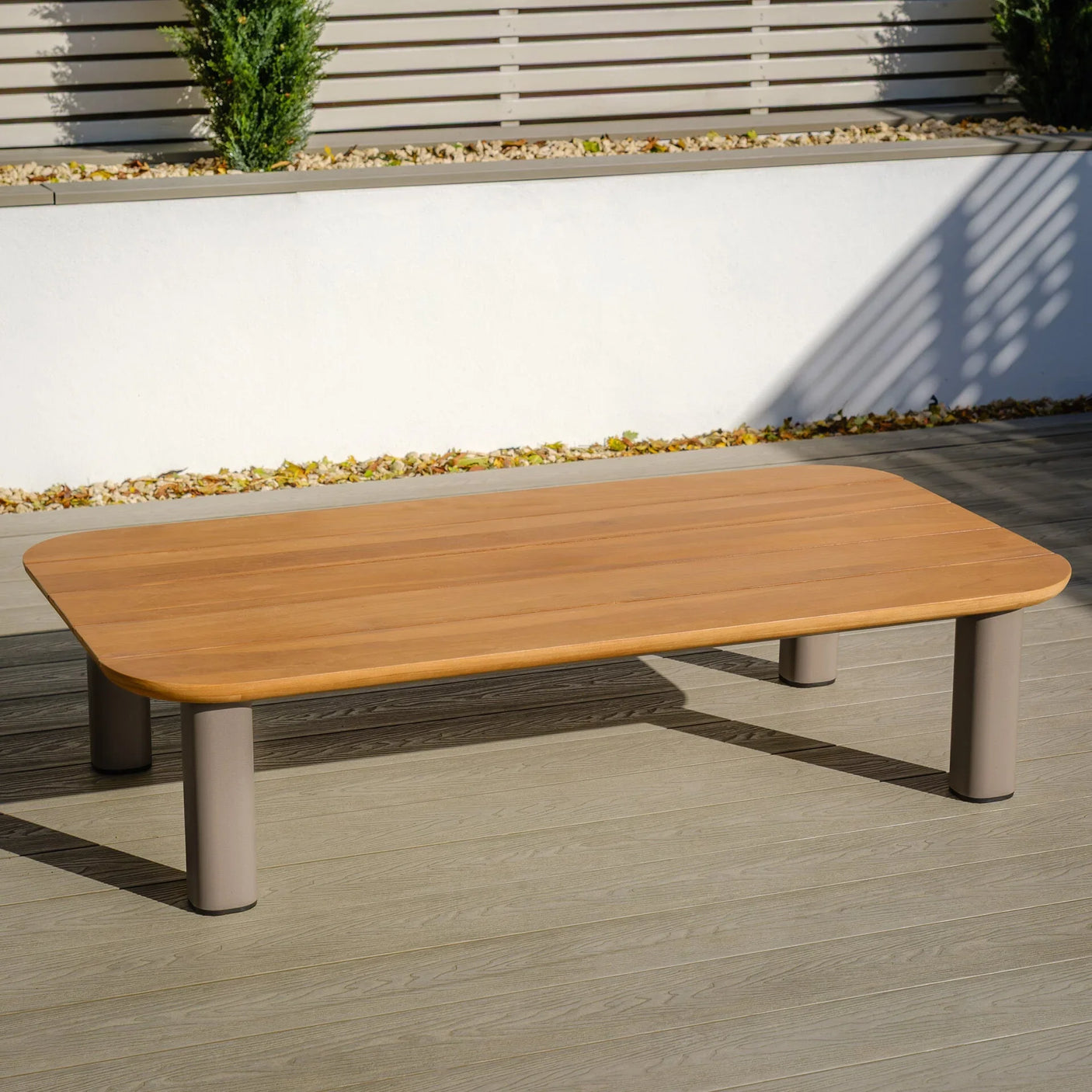 Rectangular outdoor coffee table with wood-effect top and beige metal legs on decking