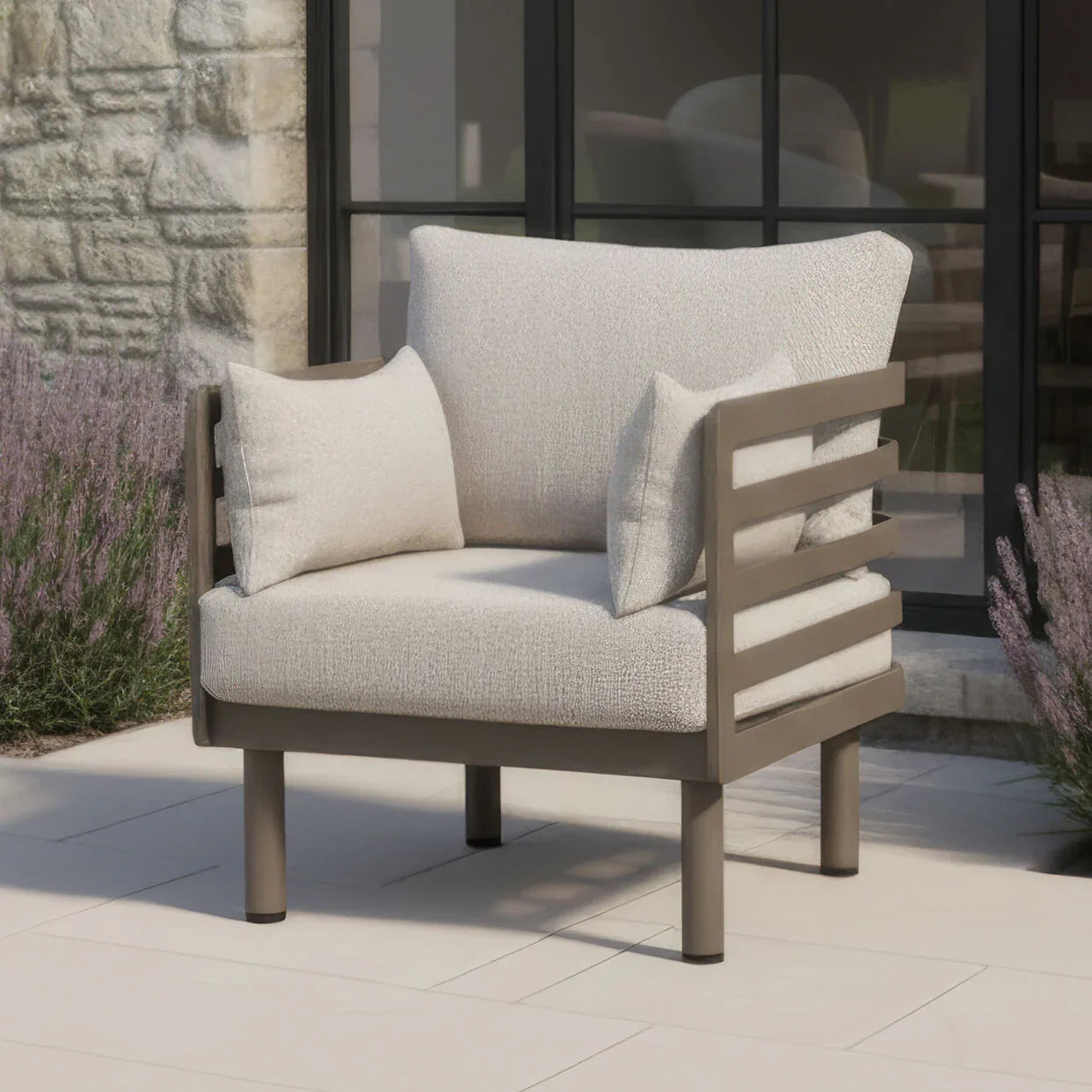 Beige outdoor armchair with metal frame and cushions on patio near glass doors