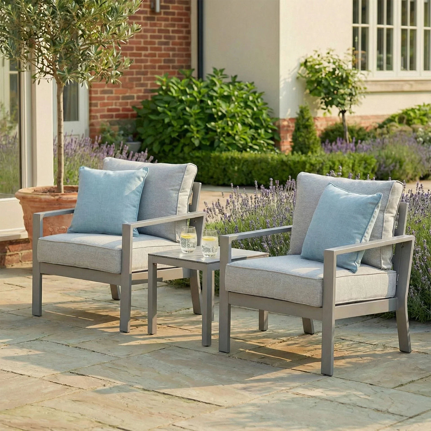 Grey outdoor garden armchair set with blue cushions and side table on stone patio
