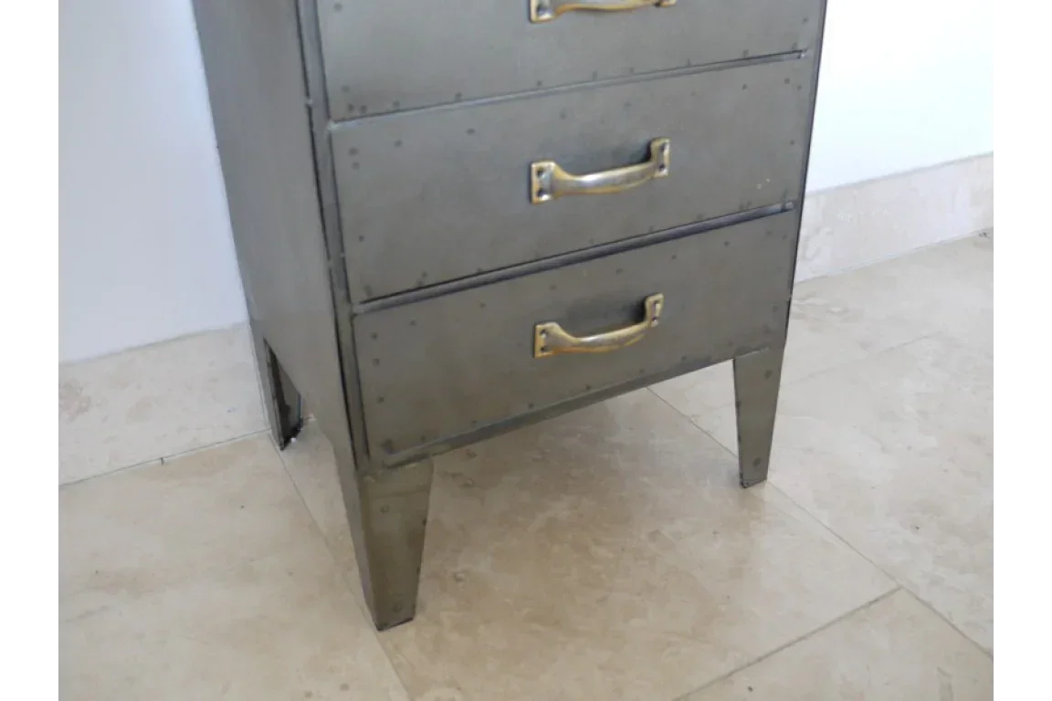 Metal drawer cabinet with brass handles and rivet details on tiled floor