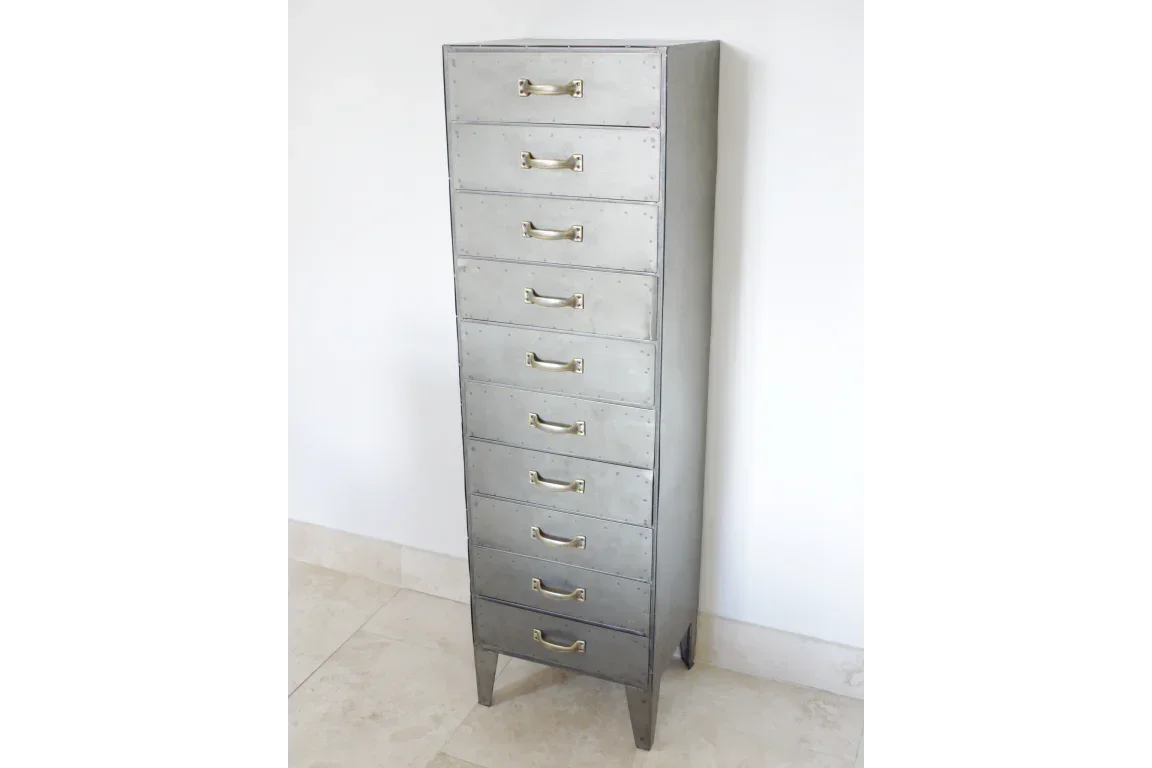 Tall metal chest of drawers with nine handles and rivet detail on tiled floor