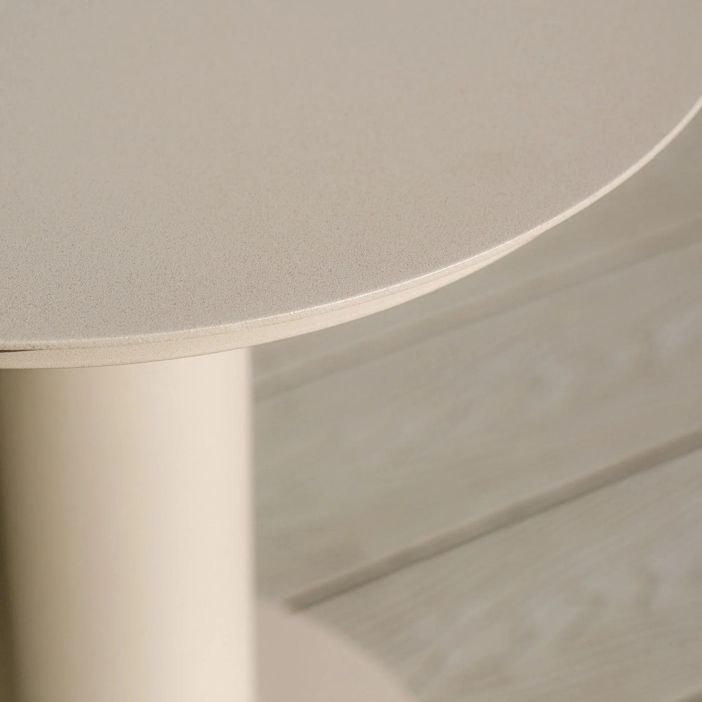Beige round side table with smooth finish and cylindrical base, close-up angle
