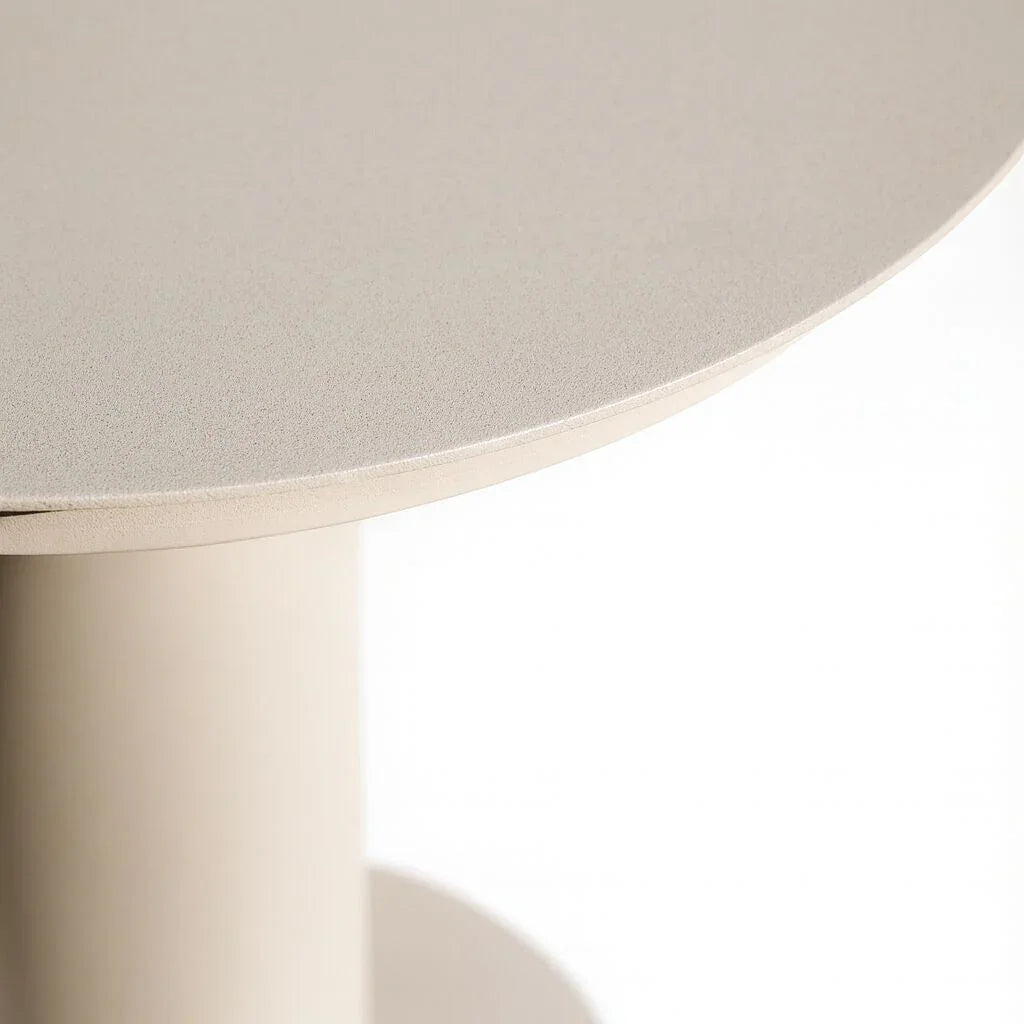 Round beige side table with smooth textured top and cylindrical base, close-up view