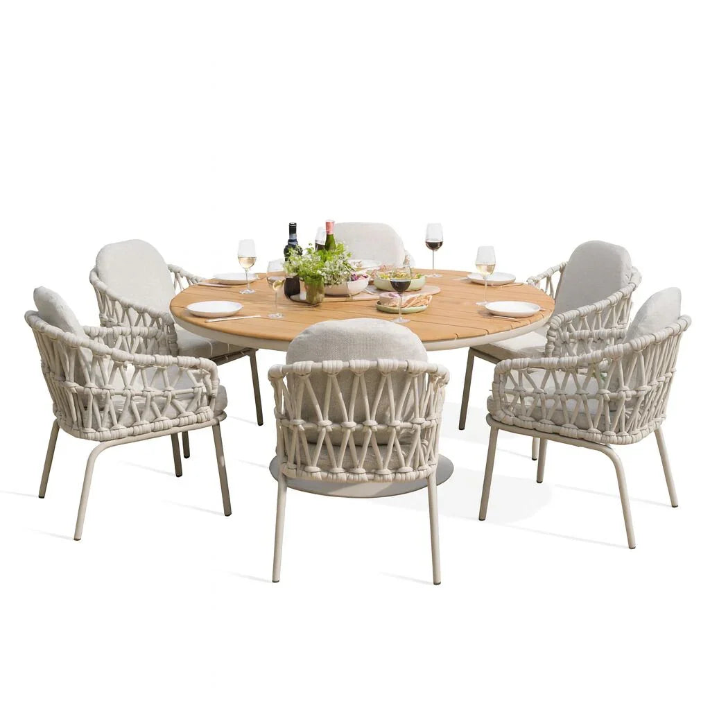 Round wooden garden dining table with six rope woven armchairs and tableware set for a meal