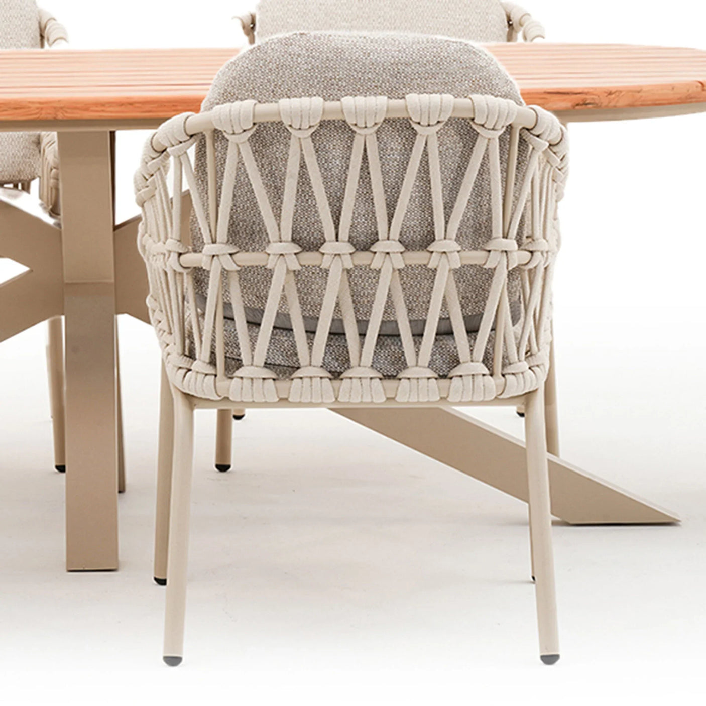 Beige rope woven outdoor dining chair with cushioned seat and light wood table