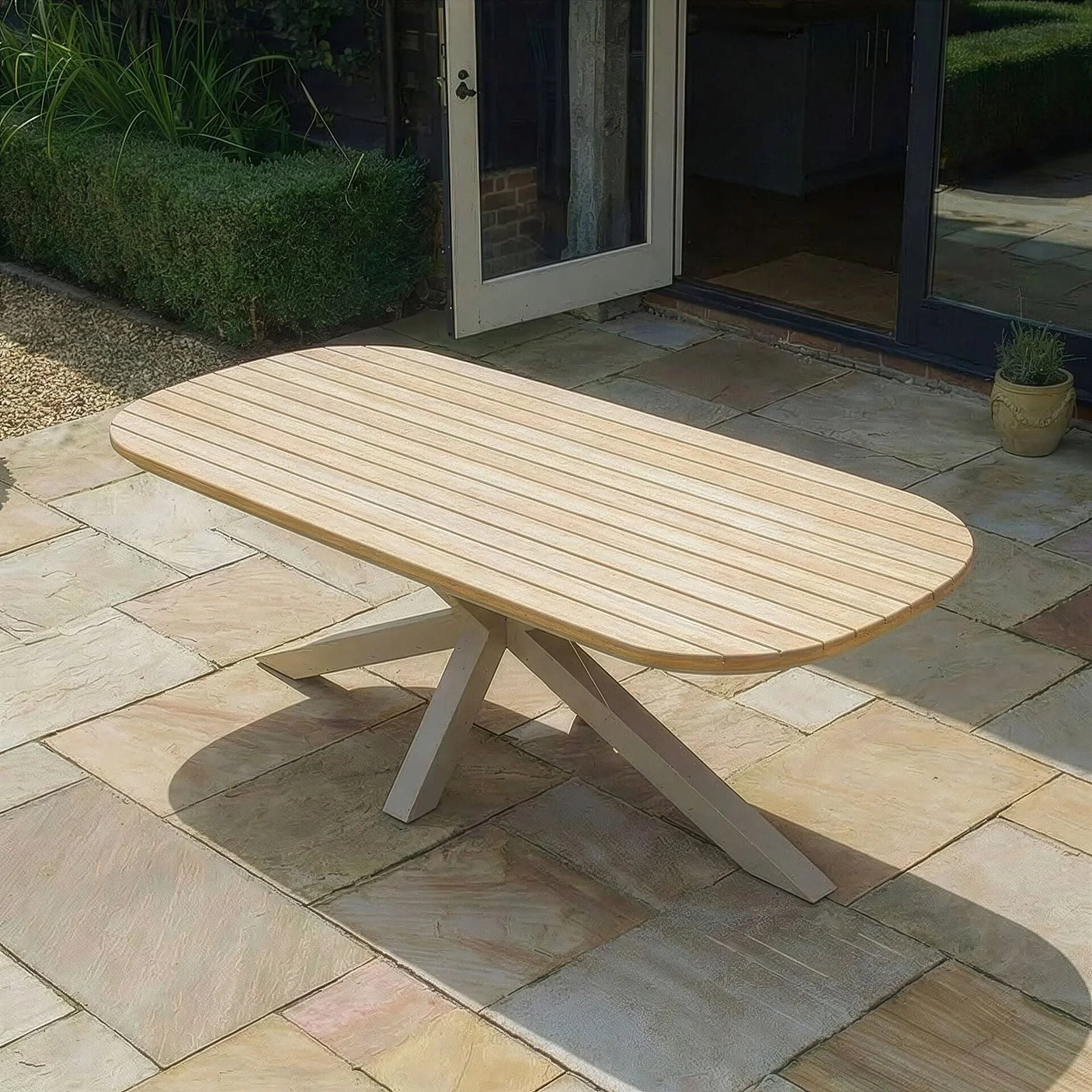 Rectangular wooden outdoor dining table with slatted top on stone patio