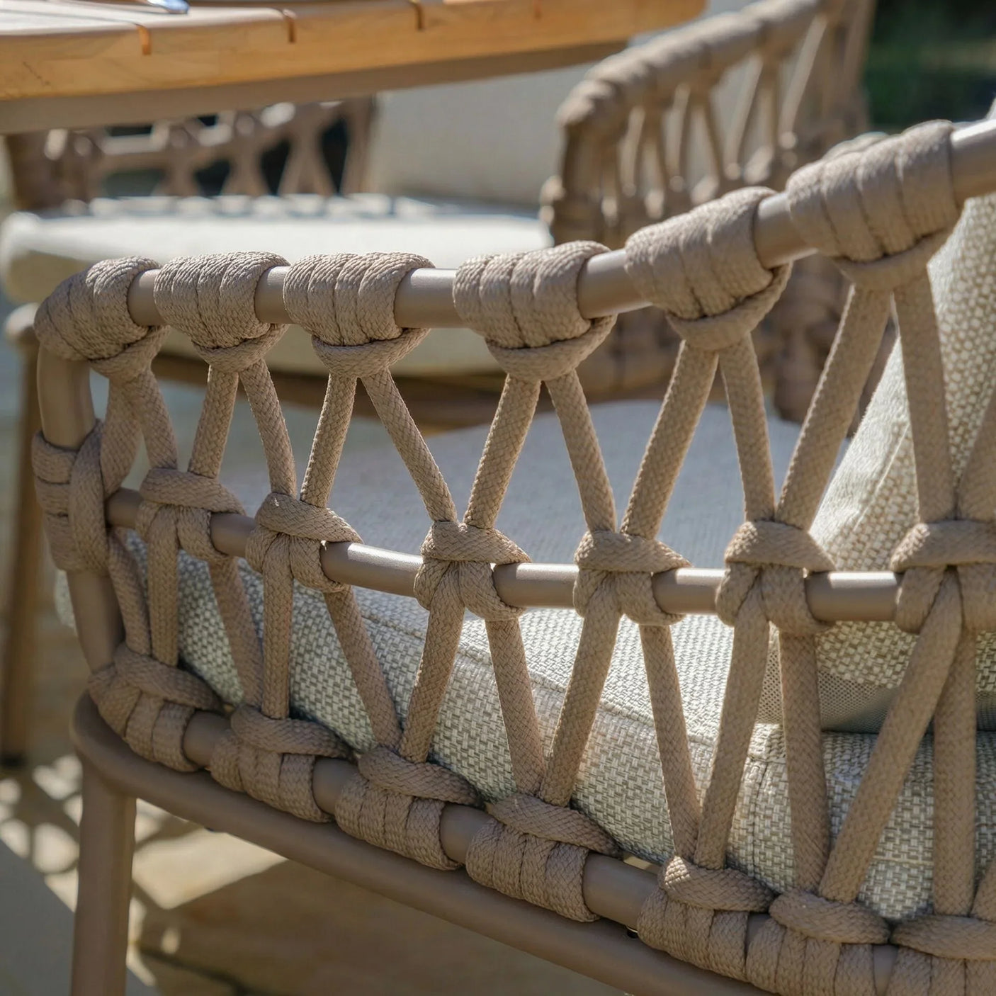 Beige rope outdoor dining chair with woven backrest and light cushion detail
