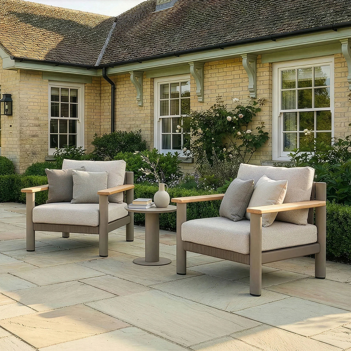 Outdoor garden armchairs with beige cushions and wooden arms beside round patio table