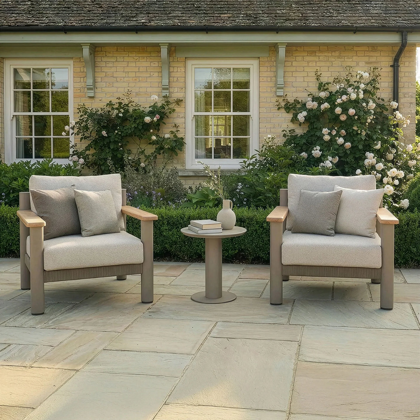 Outdoor patio furniture set with two beige armchairs and side table on stone terrace