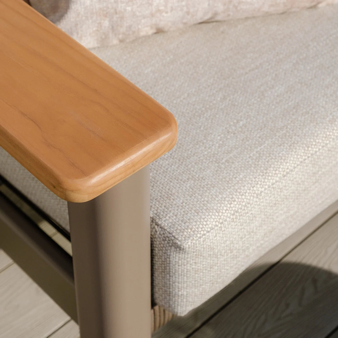 Metal and wood armrest with beige outdoor sofa cushion on patio decking