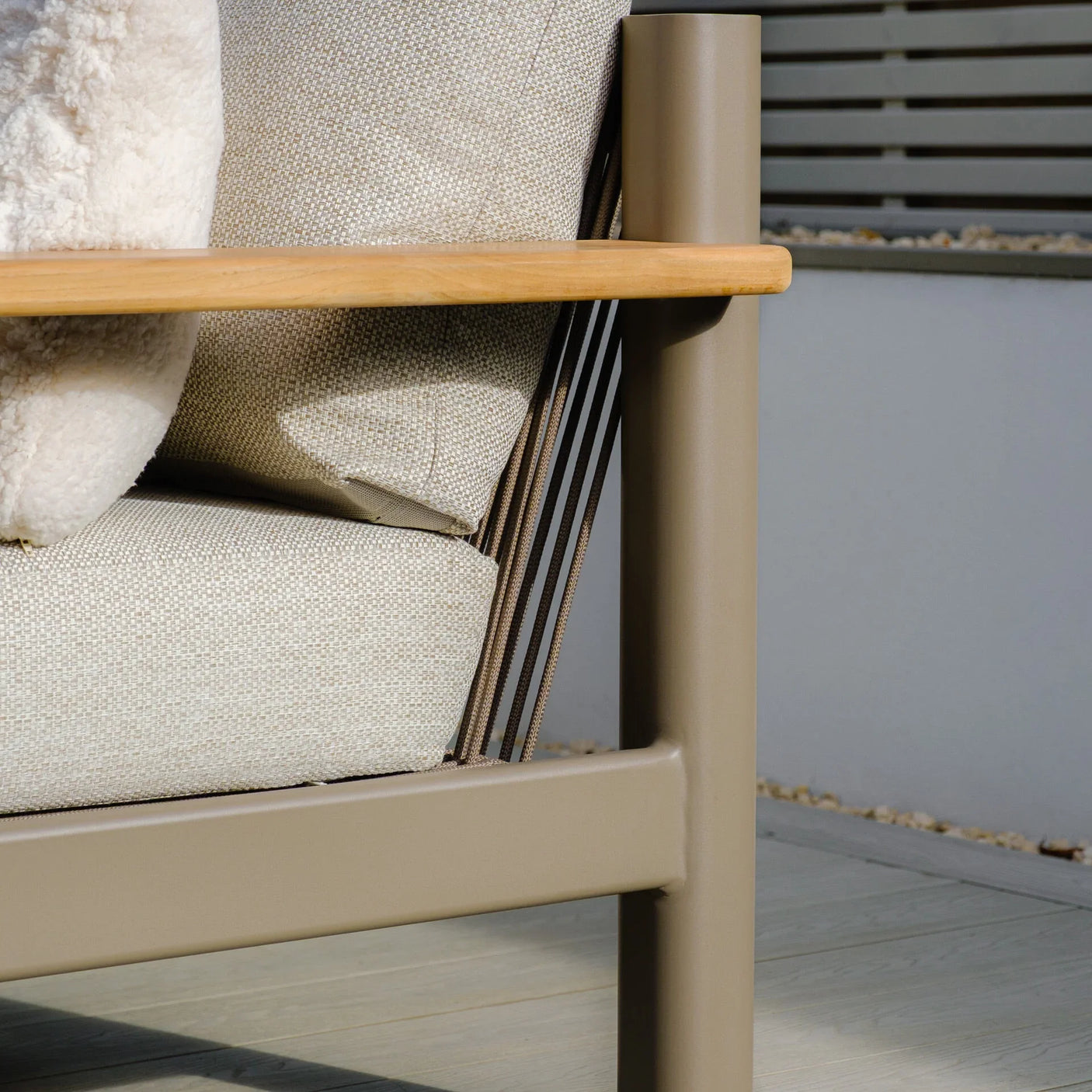 Beige outdoor sofa corner with padded cushion and wooden armrest detail