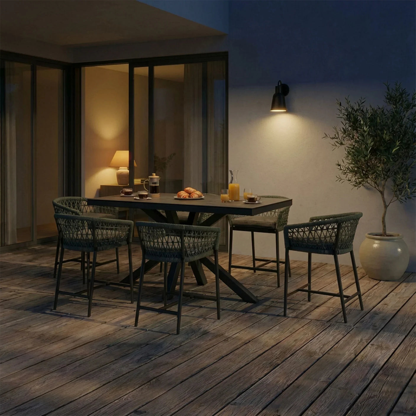Outdoor dining set with woven chairs and black table on patio, evening setting with food served