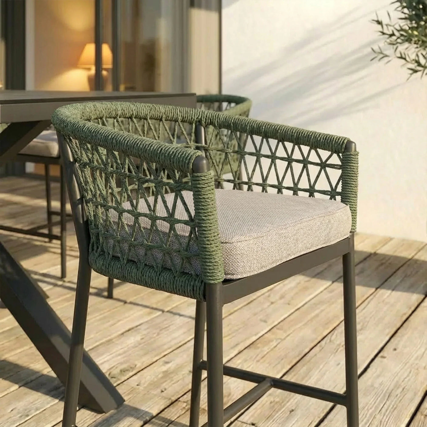 Green rope outdoor dining chair with beige cushion on wooden patio beside table
