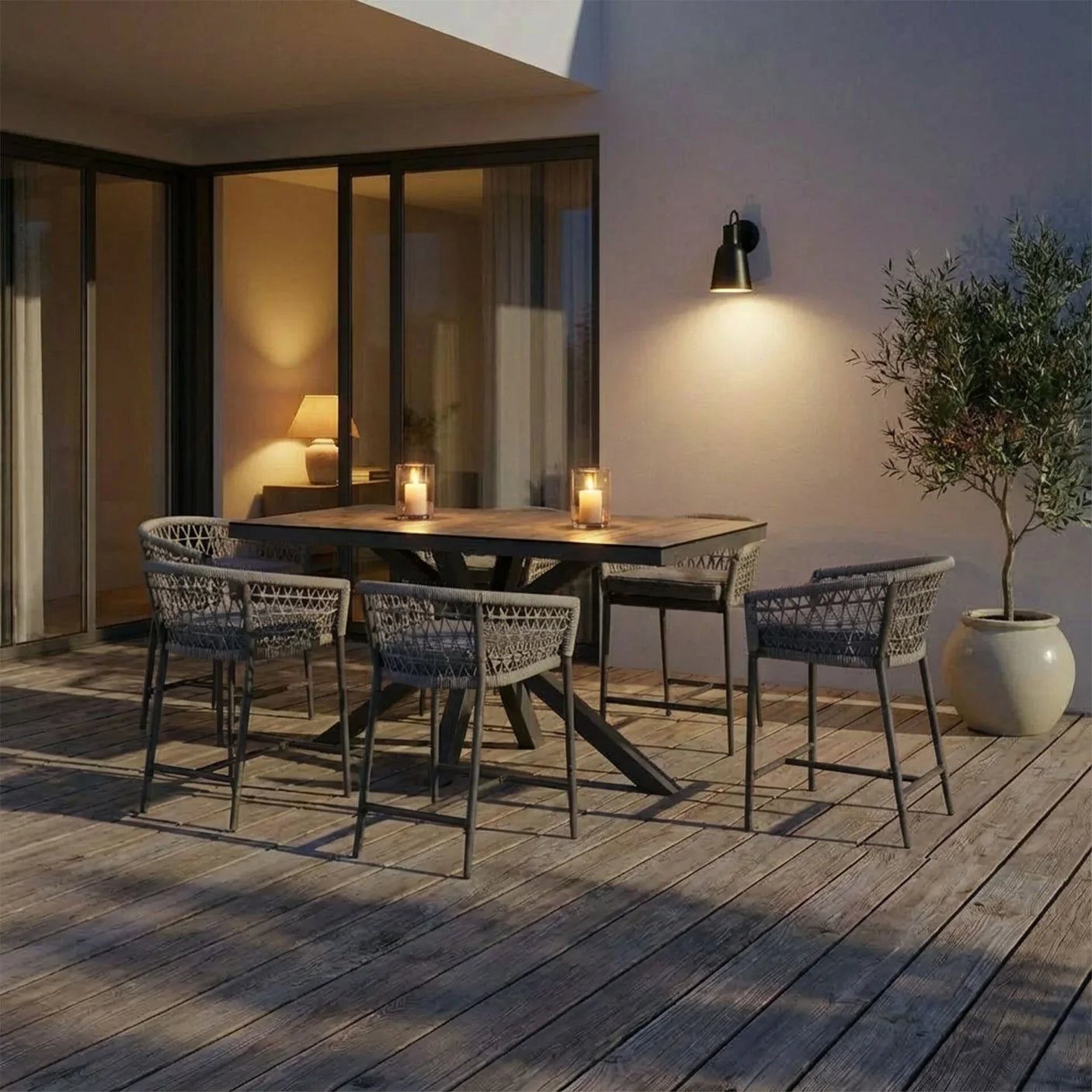 Outdoor dining set with wooden table, woven chairs and candles on patio decking