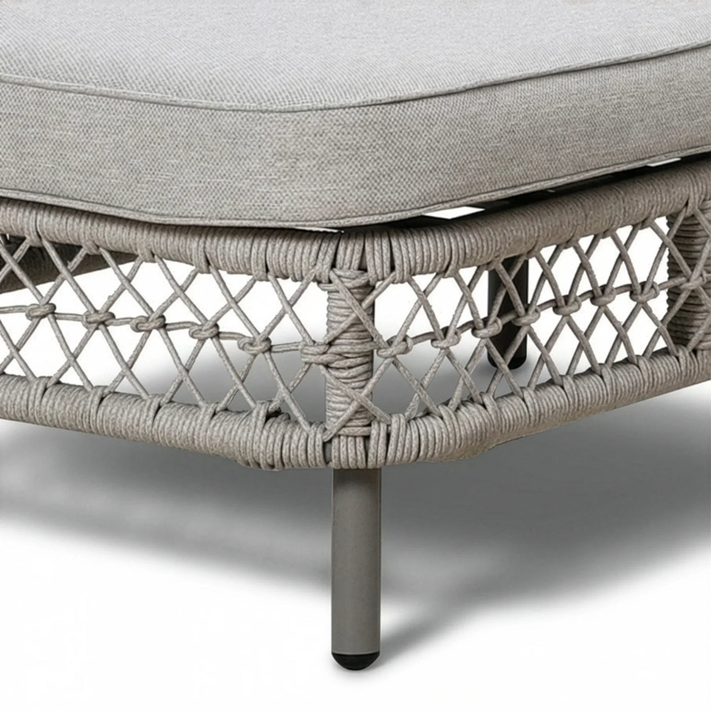 Close-up of grey rattan sofa corner with metal legs and textured fabric cushion