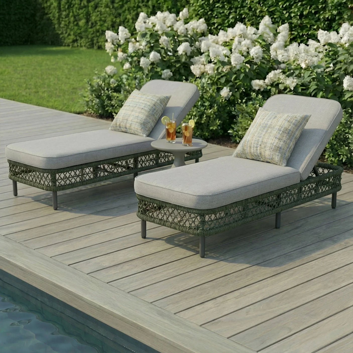 Outdoor rattan sun loungers with grey cushions poolside and drinks on side table