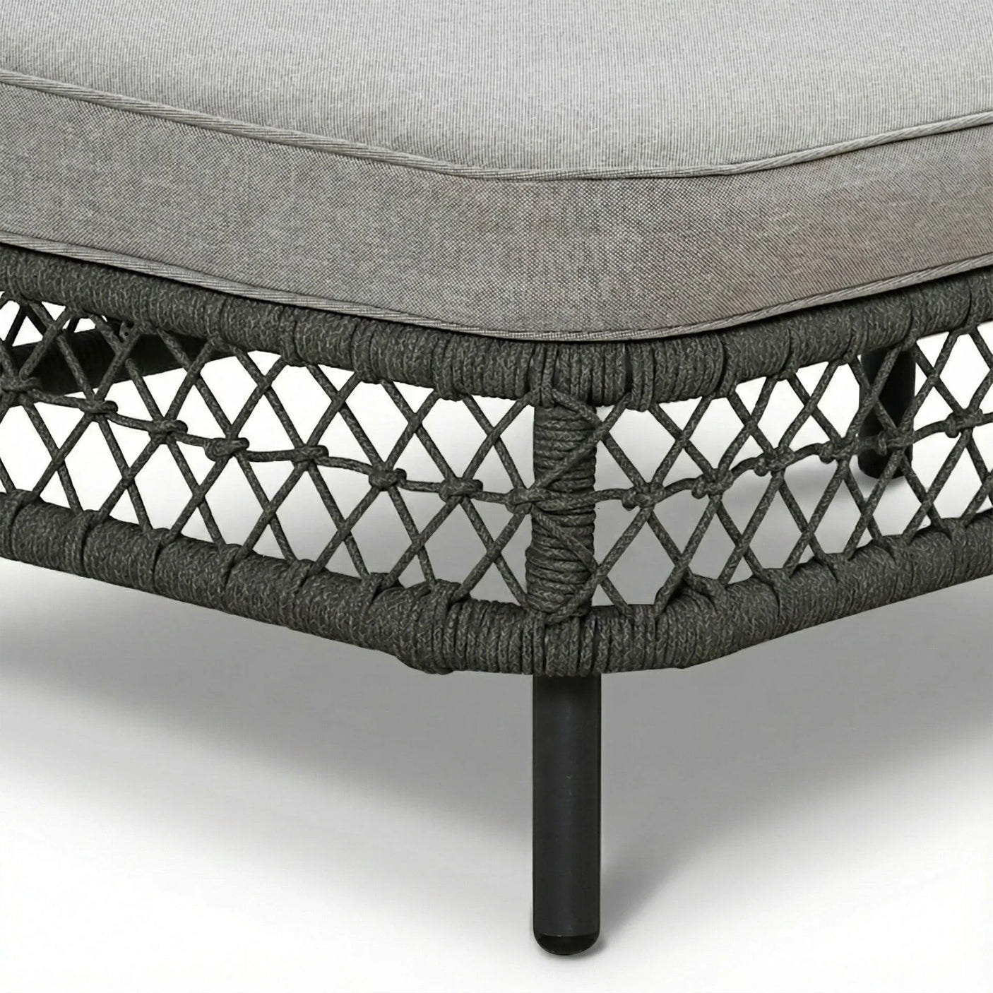 Closeup of grey rattan outdoor sofa with thick cushion and black metal legs
