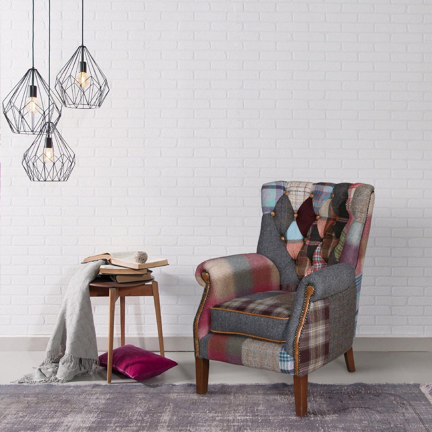 Patchwork accent armchair with wooden legs beside a side table and pendant lights