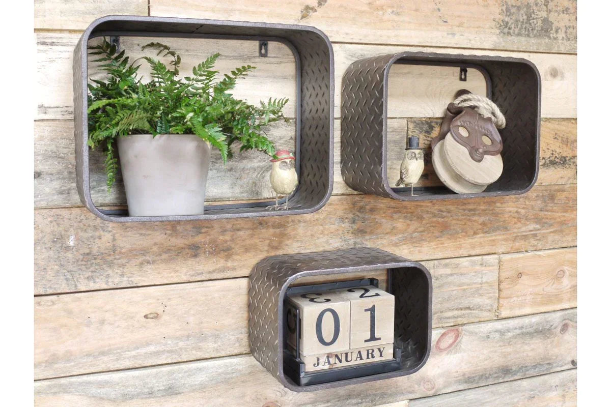 Set of three metal wall shelves with diamond pattern holding decor on rustic wood panel