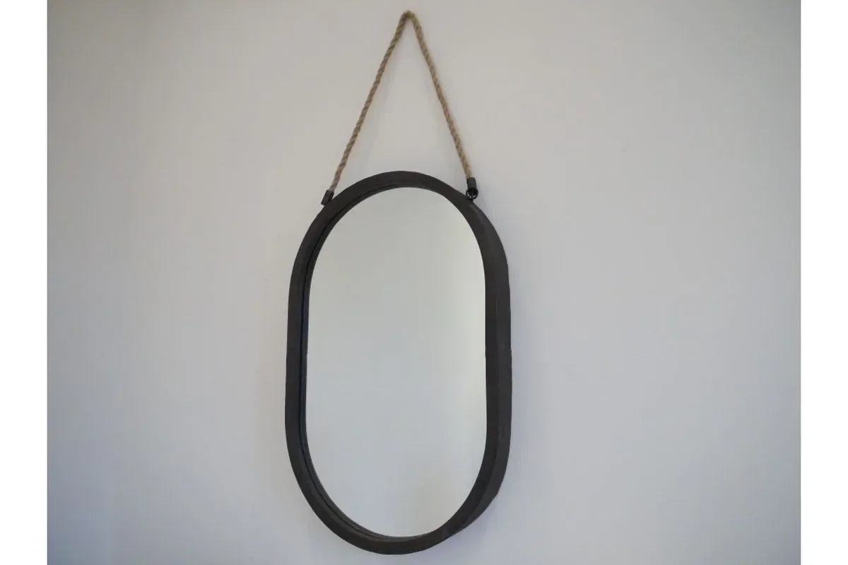 Oval wall mirror with black frame and rope hanging against white wall
