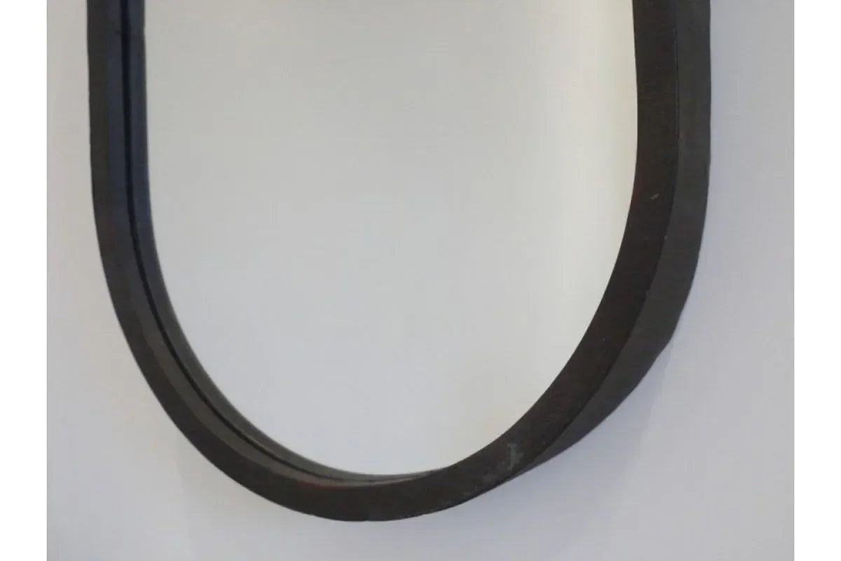Close-up of black metal wall mirror frame against light background