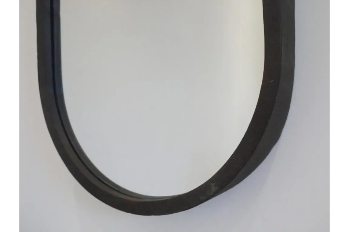 Black metal mirror frame with curved edge against white wall