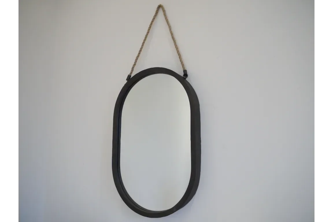Oval wall mirror with black frame and rope hanging on white background