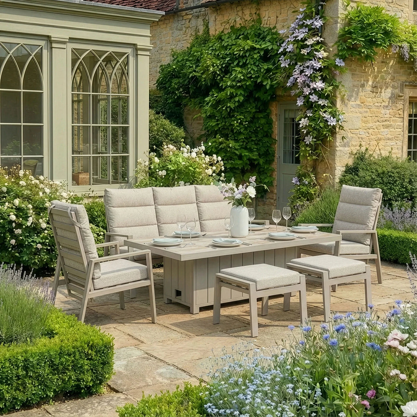Beige cushioned outdoor dining set with table, chairs and benches on a stone patio in garden