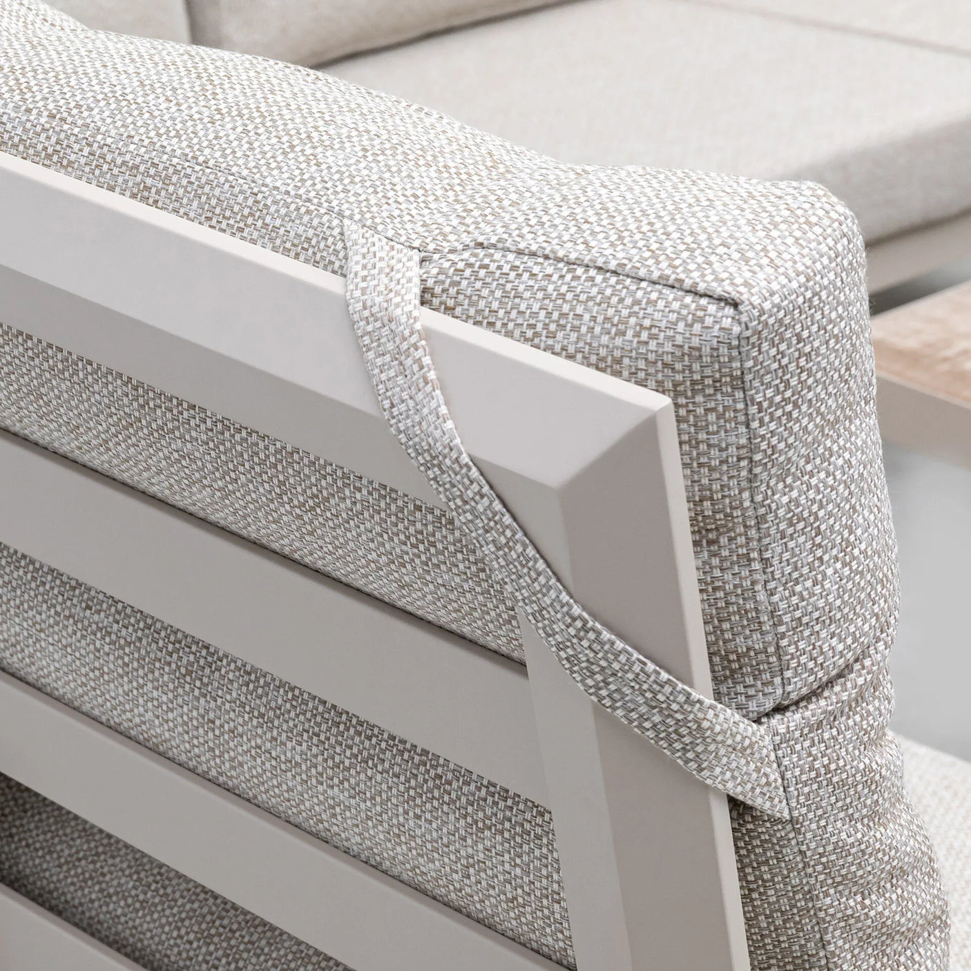 Closeup of outdoor sofa cushion with beige woven fabric and strap on slatted metal frame