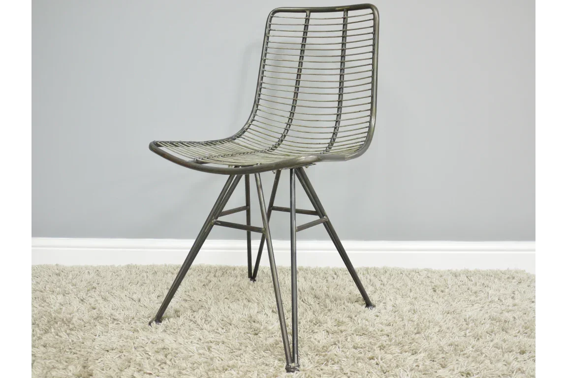 Metal wire dining chair with angled legs on a beige carpet against a grey wall