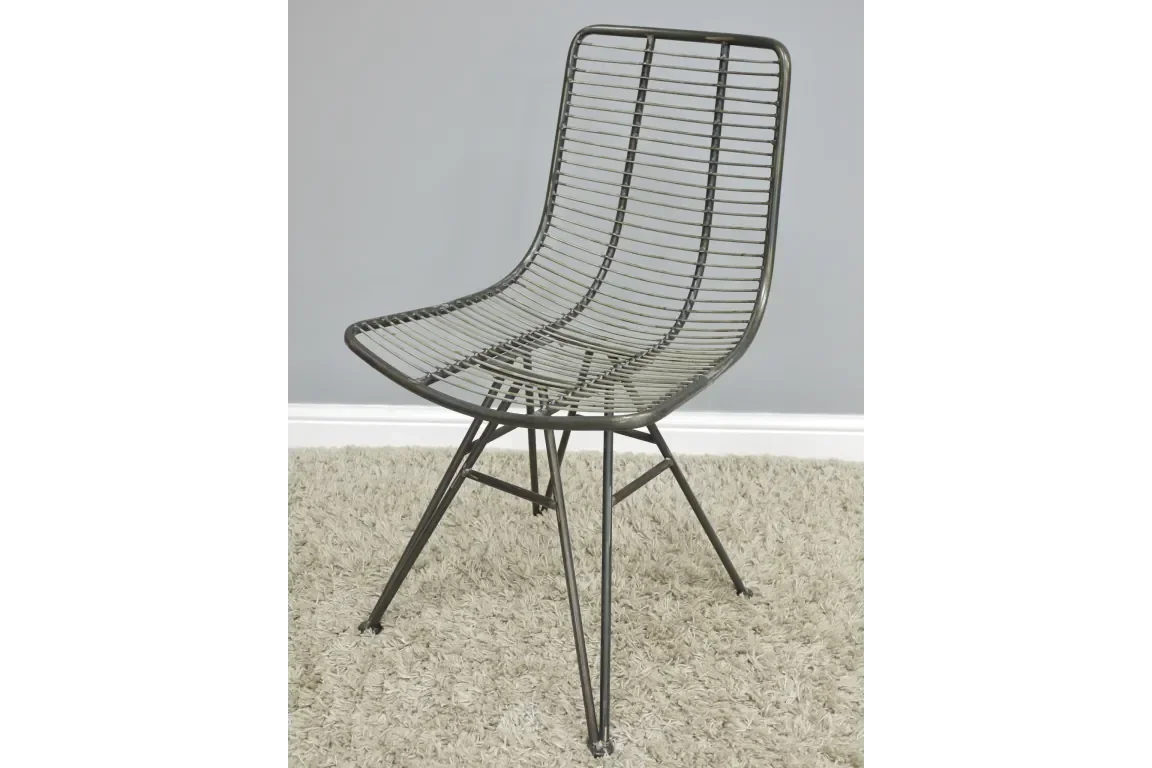 Black metal dining chair with openwork design on beige carpet against grey wall