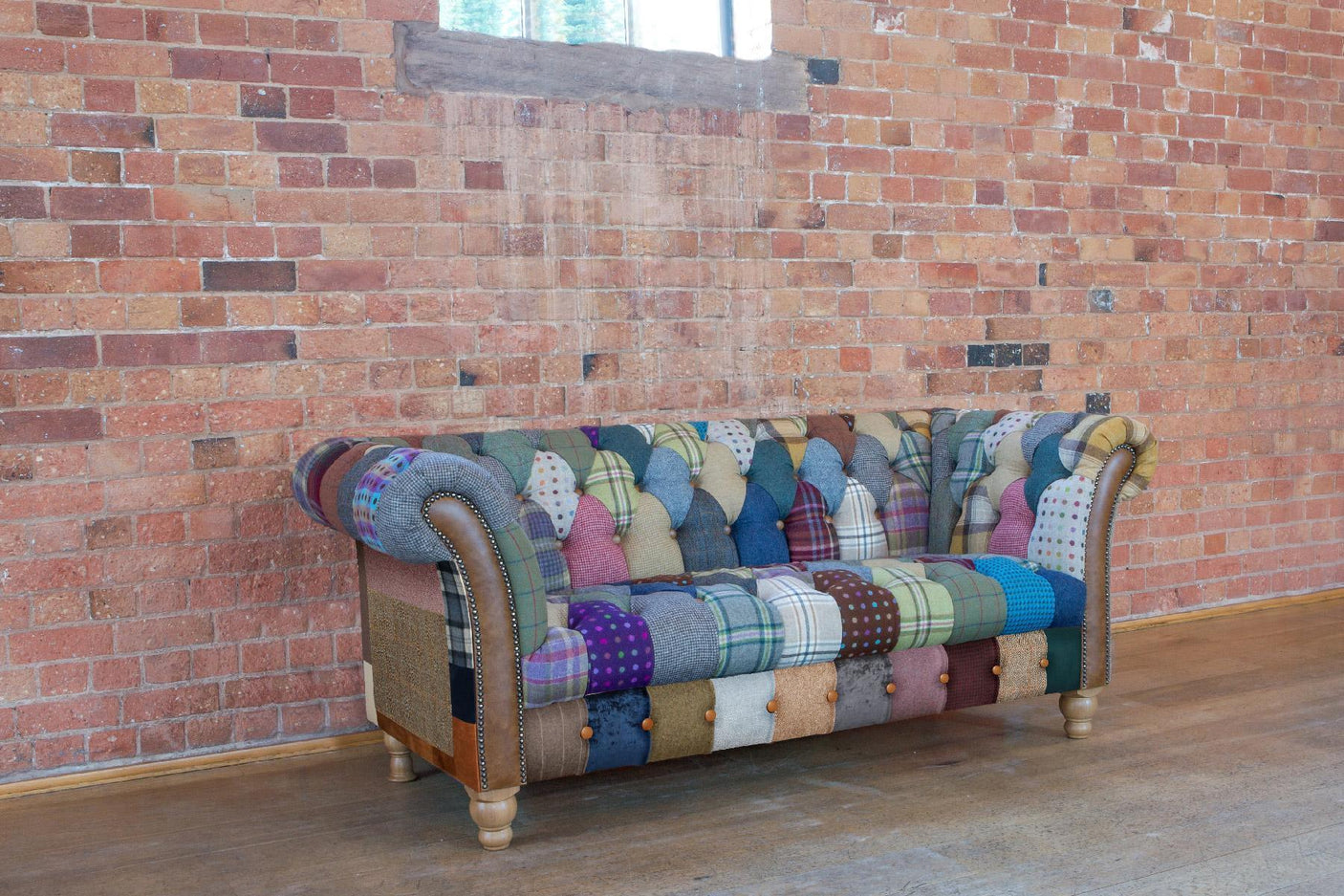 Patchwork fabric Chesterfield sofa with wooden legs against exposed brick wall