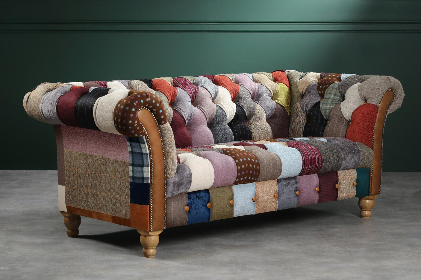 Patchwork fabric Chesterfield sofa with button tufting and wooden legs against green wall