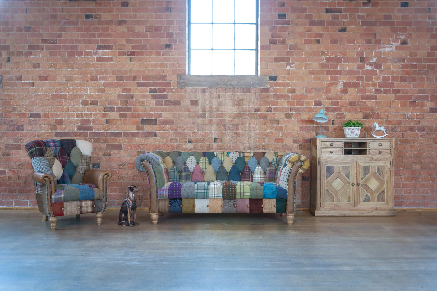 Patchwork fabric sofa and armchair with wooden cabinet in front of exposed brick wall
