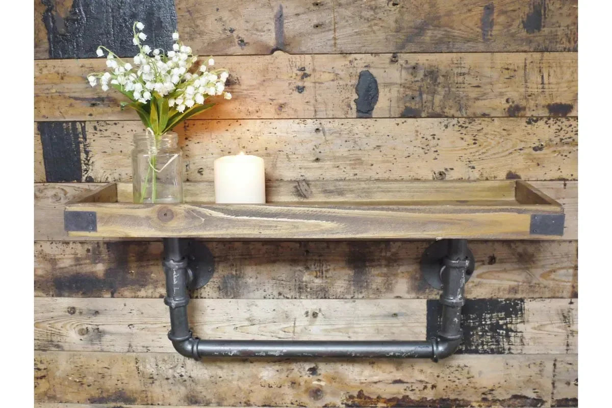 Industrial wood and metal wall shelf with black pipe brackets, vase of flowers, and candle