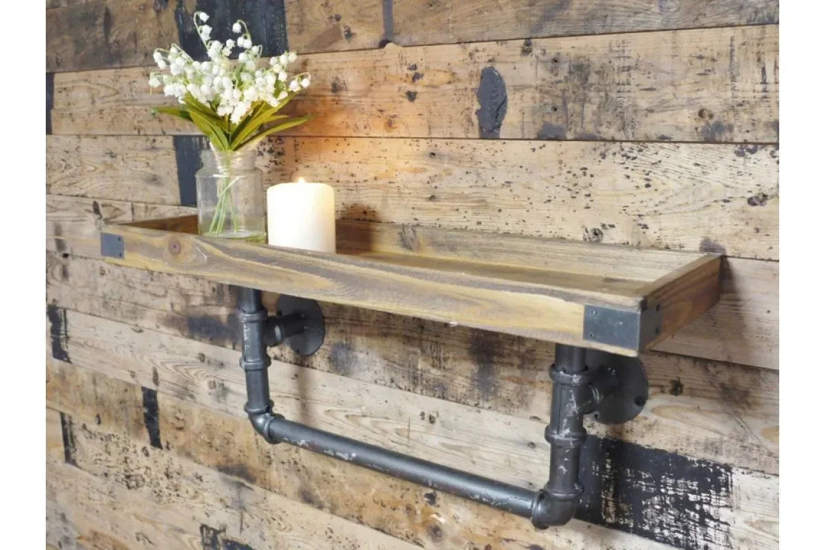Industrial wall shelf with black pipe bracket, wood panel background, vase, and candle
