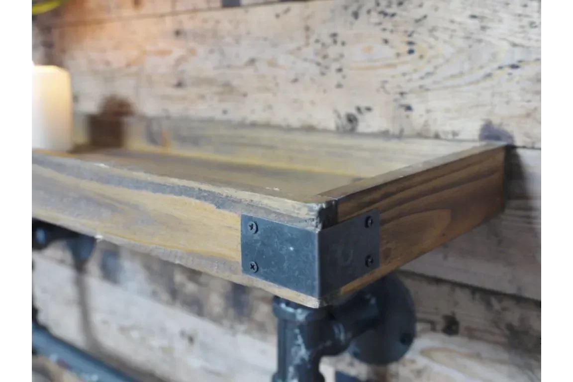 Industrial reclaimed wood shelf with black metal brackets mounted on rustic wall