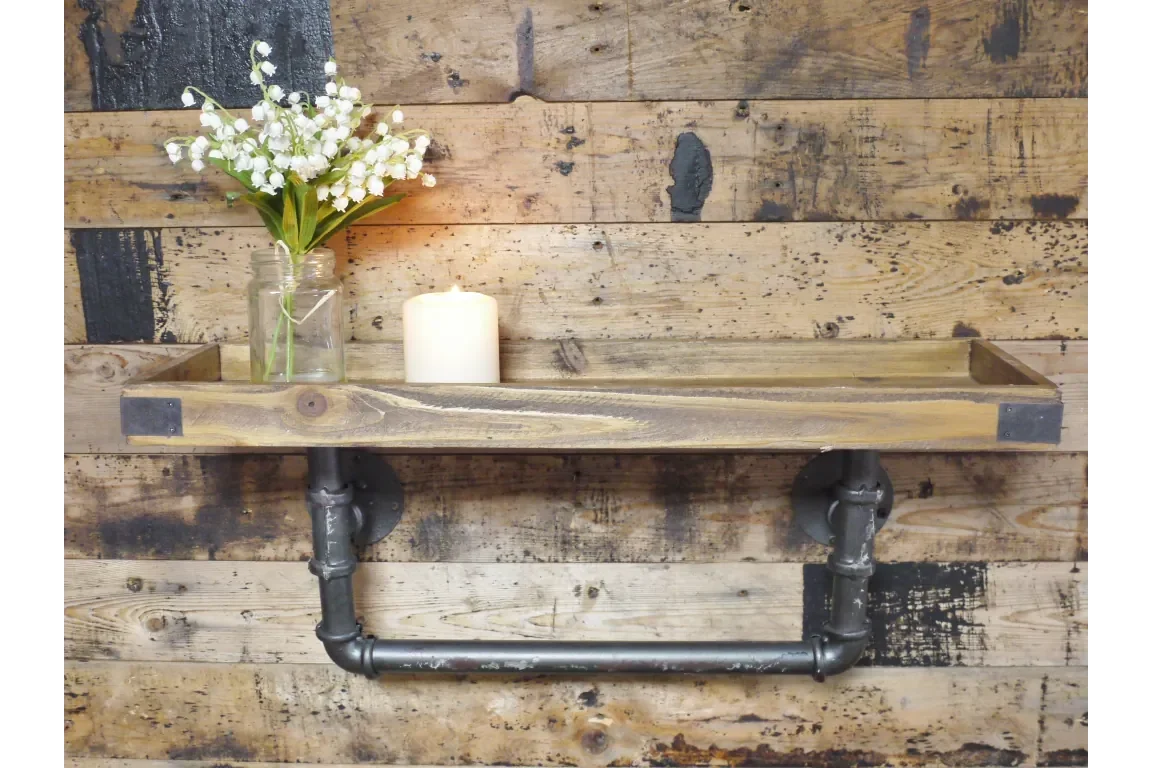 industrial pipe wall shelf with wood plank, mason jar flowers, and candle against rustic wall
