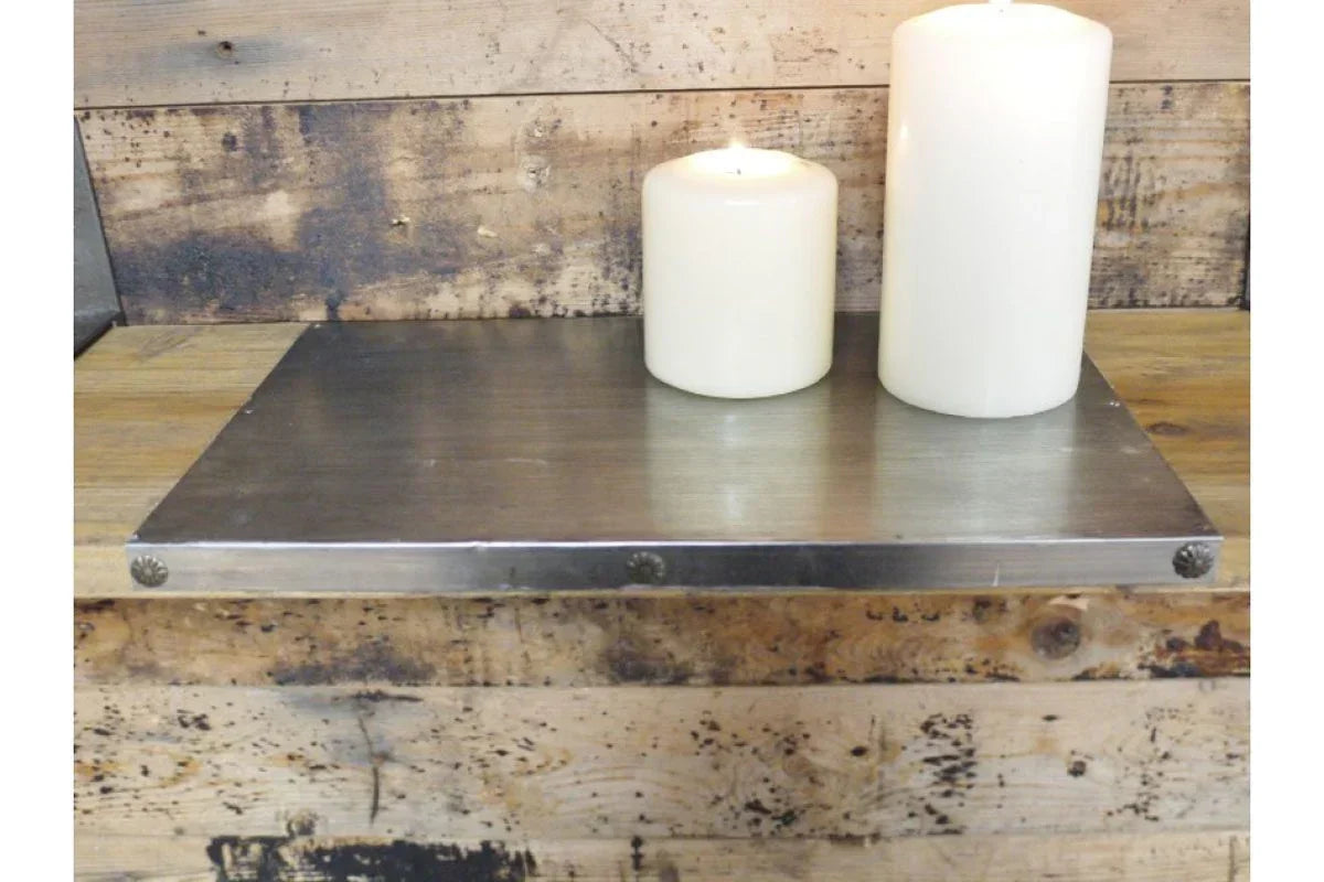 Metal wall shelf with two white pillar candles on rustic wood background