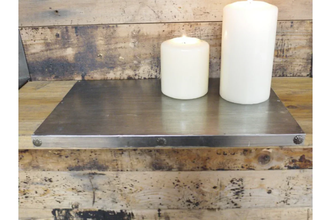 Industrial style metal wall shelf with two white pillar candles on rustic wood background