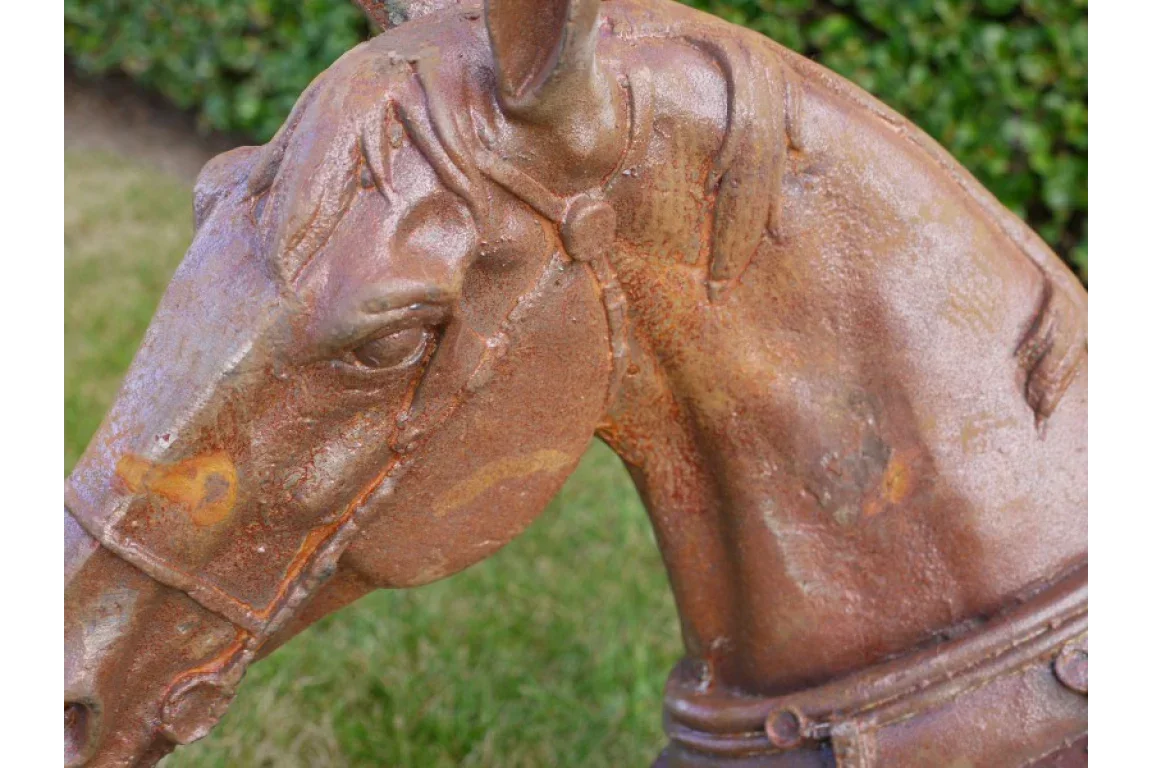 Rustic cast iron horse head garden ornament with detailed bridle, shown outdoors on grass