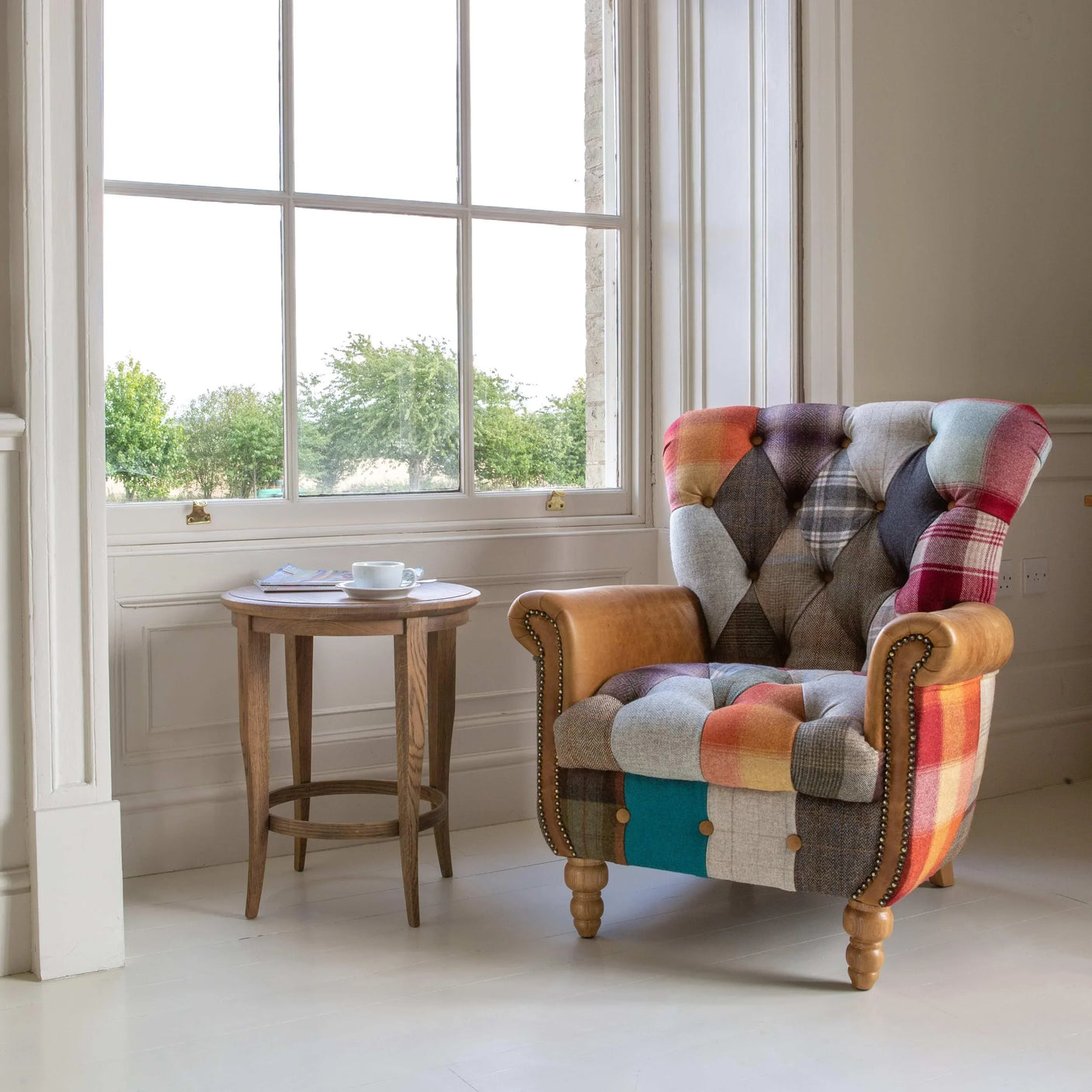 Patchwork fabric armchair with button detailing beside wooden side table in bright living room